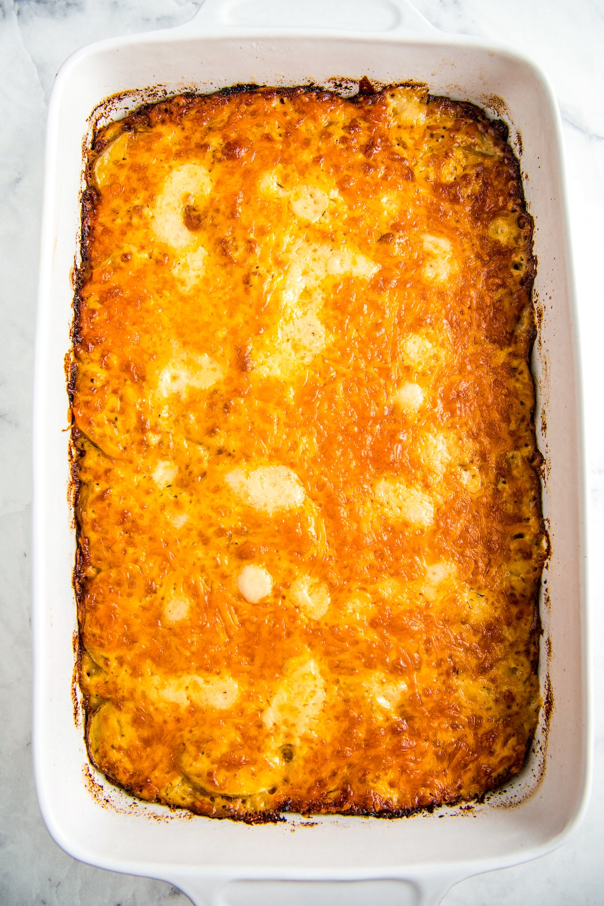 Baked casserole with melted cheese on top in a white casserole dish.