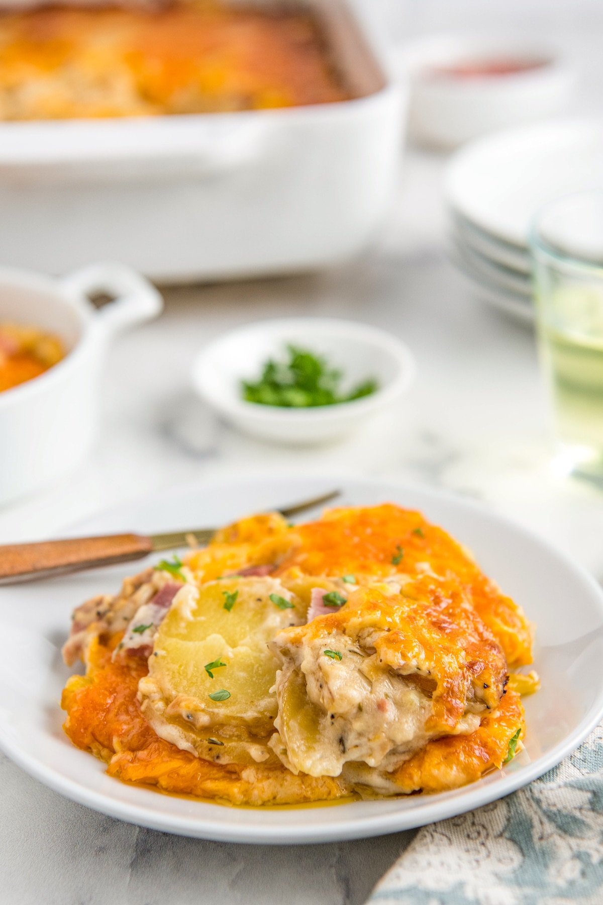 A plate filled with scalloped potatoes with ham casserole on a white plate.