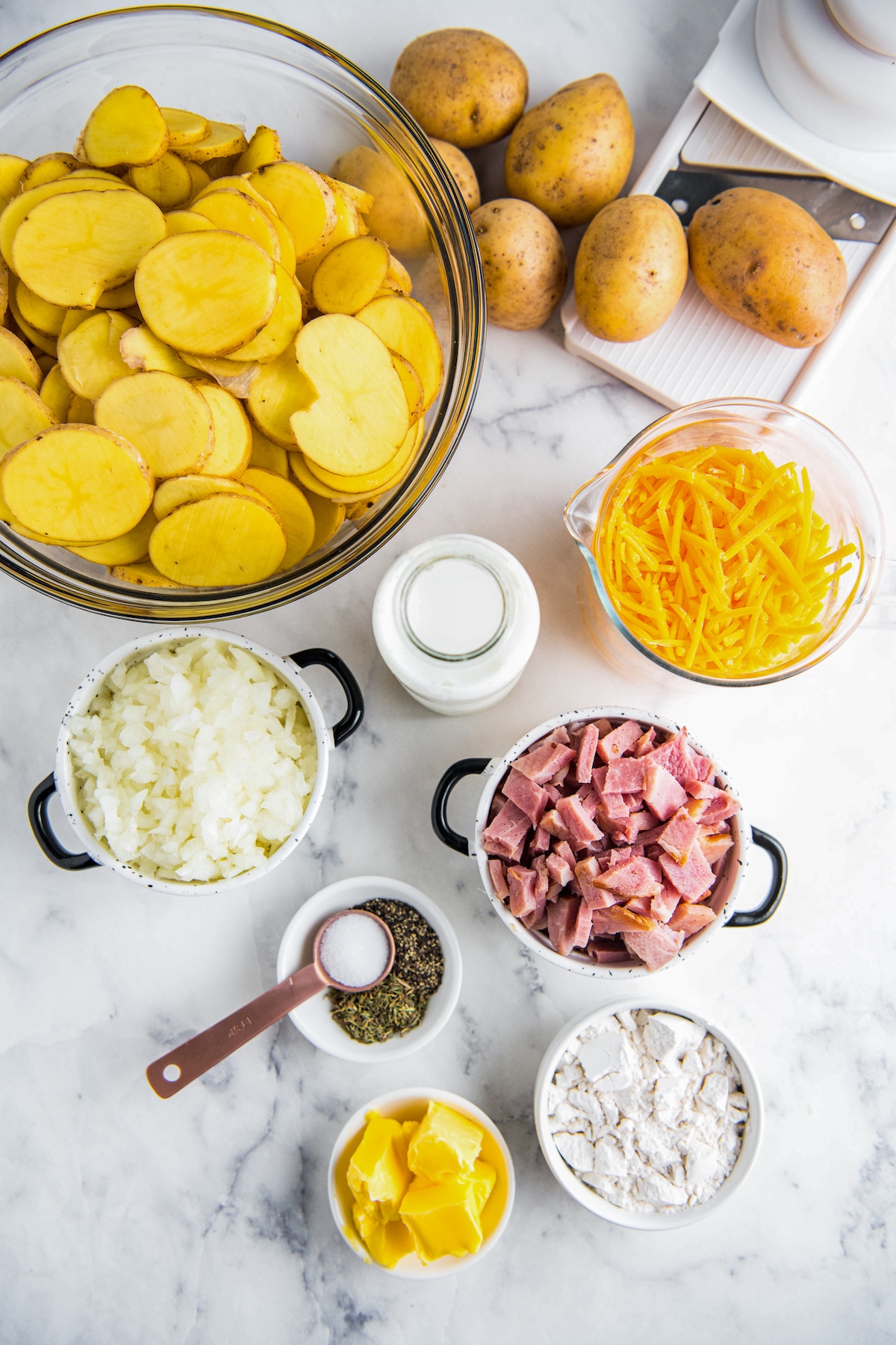 Ingredients for a casserole arranged on a marble countertop with bowls.