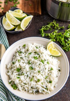 Cilantro lime rice in a white bowl with a wedge of lime.