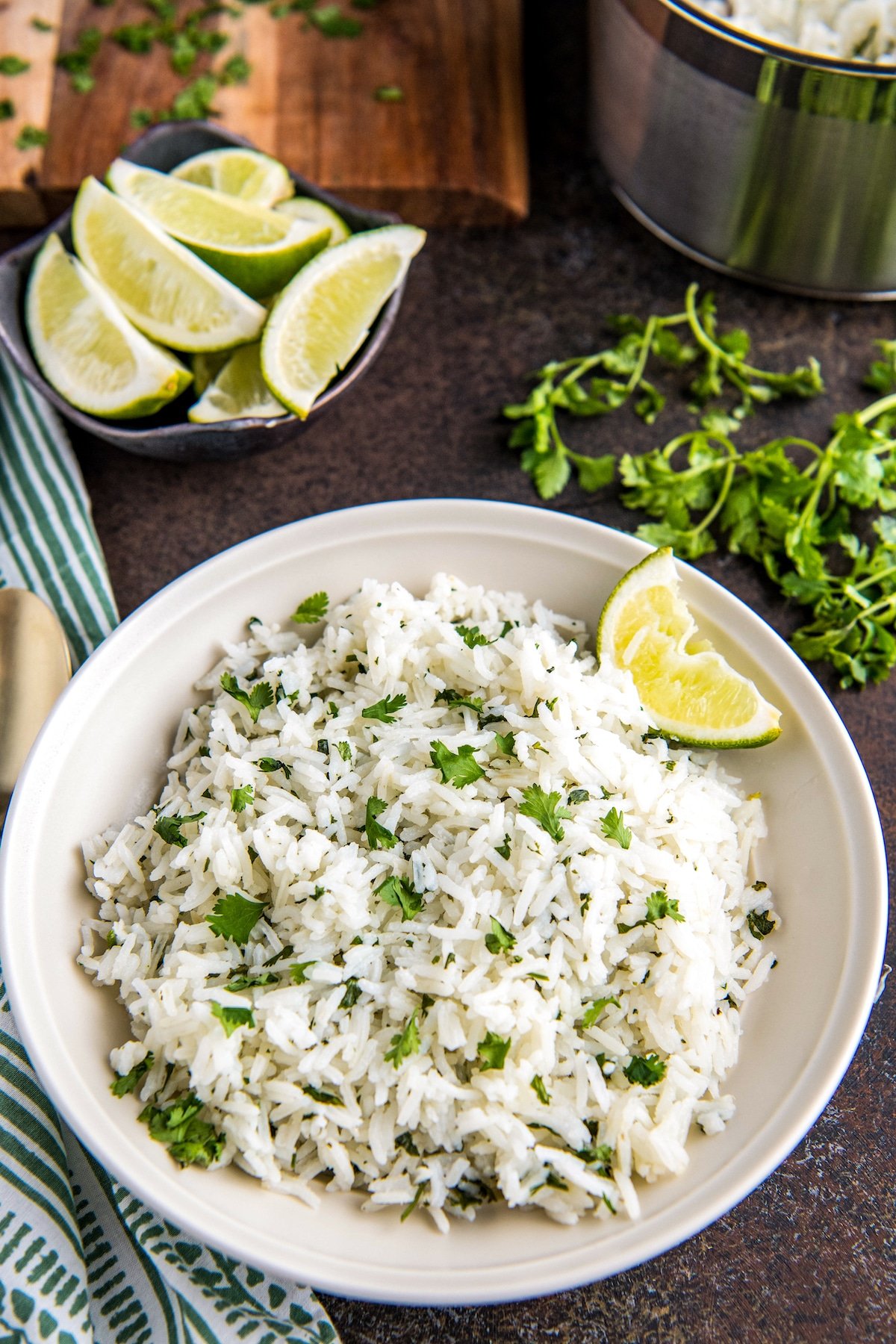Cilantro lime rice in a white bowl with a wedge of lime.