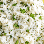 A bowl of cilantro lime rice with a wedge of lime.