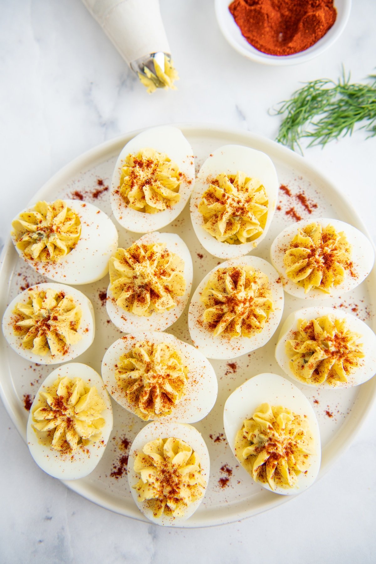 Deviled eggs on a white plate with paprika sprinkled on top.