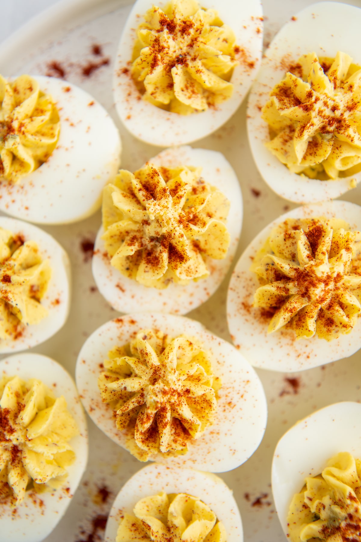 A bunch of deviled eggs on a platter with paprika sprinkled on top.