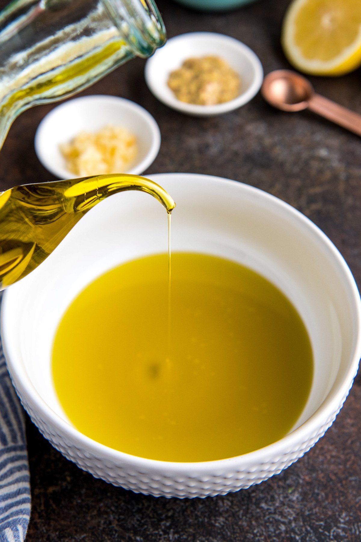 Olive oil being poured into a white bowl.