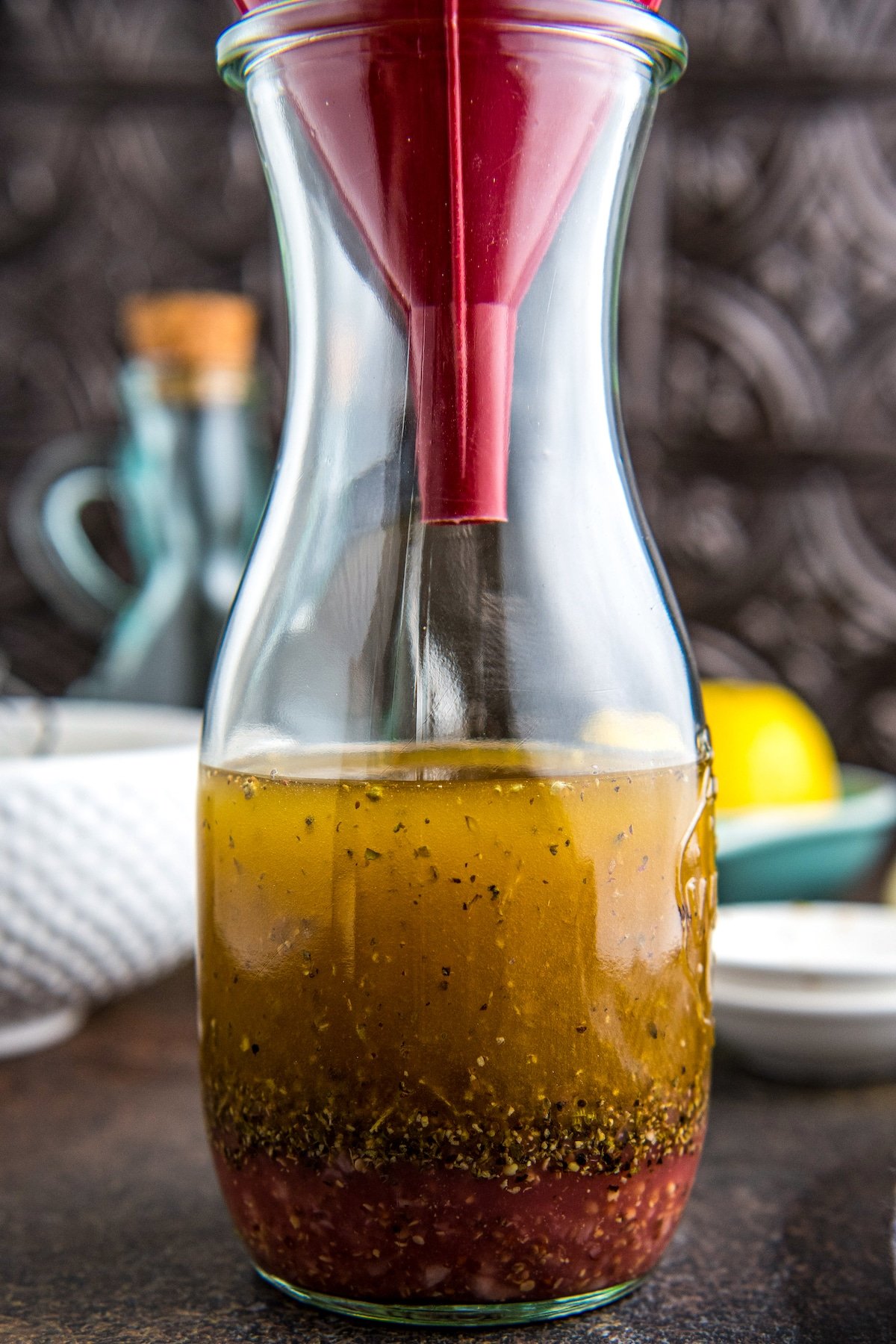 Salad dressing ingredients in a bottle with a funnel in the top.