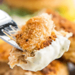 Tartar sauce on a bite of fried fish on a fork.