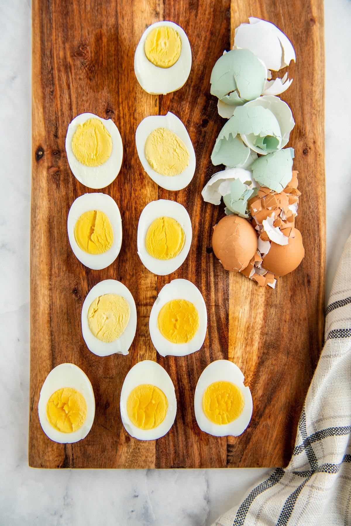 10 peeled eggs sliced in half on a cutting board.