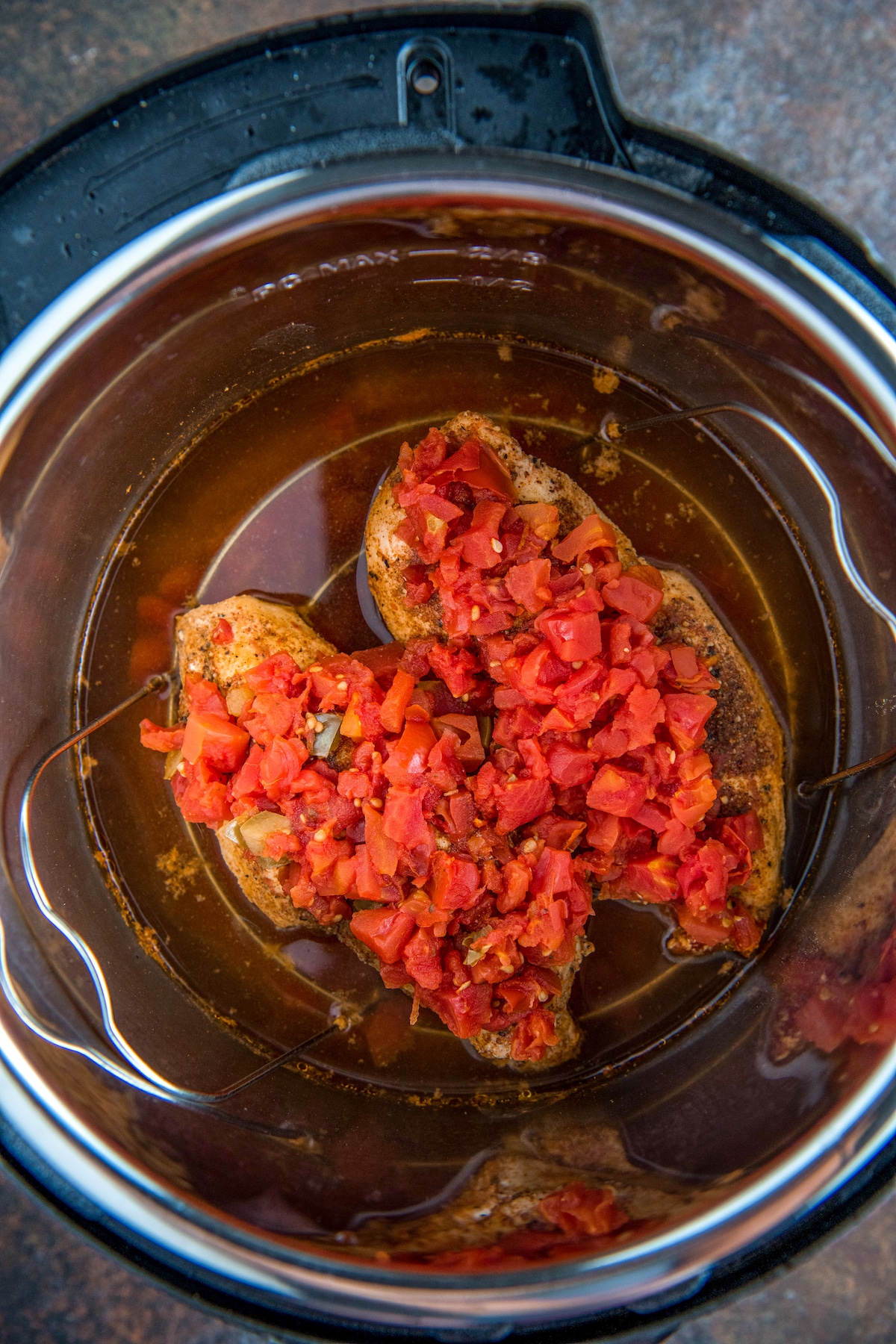 Two chicken breasts cooked in an instant pot with salsa on top.