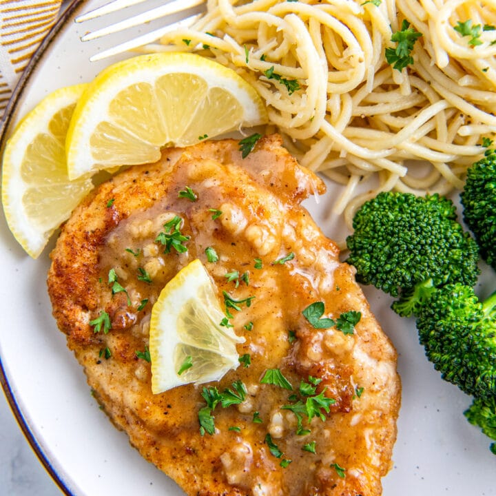 Lemon chicken on a white plate with broccoli and noodles.