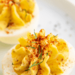 A deviled egg with paprika and chives on top.