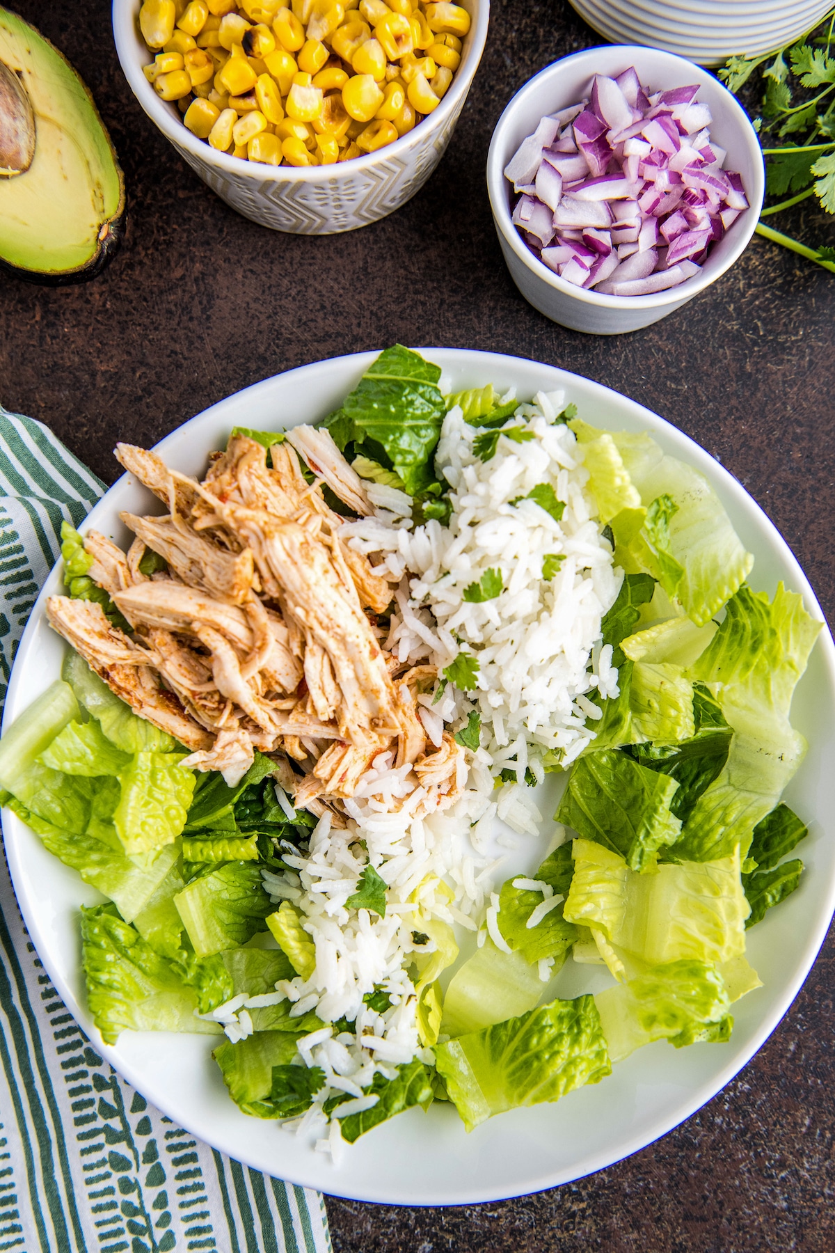 A bowl with lettuce, rice and chicken in it.