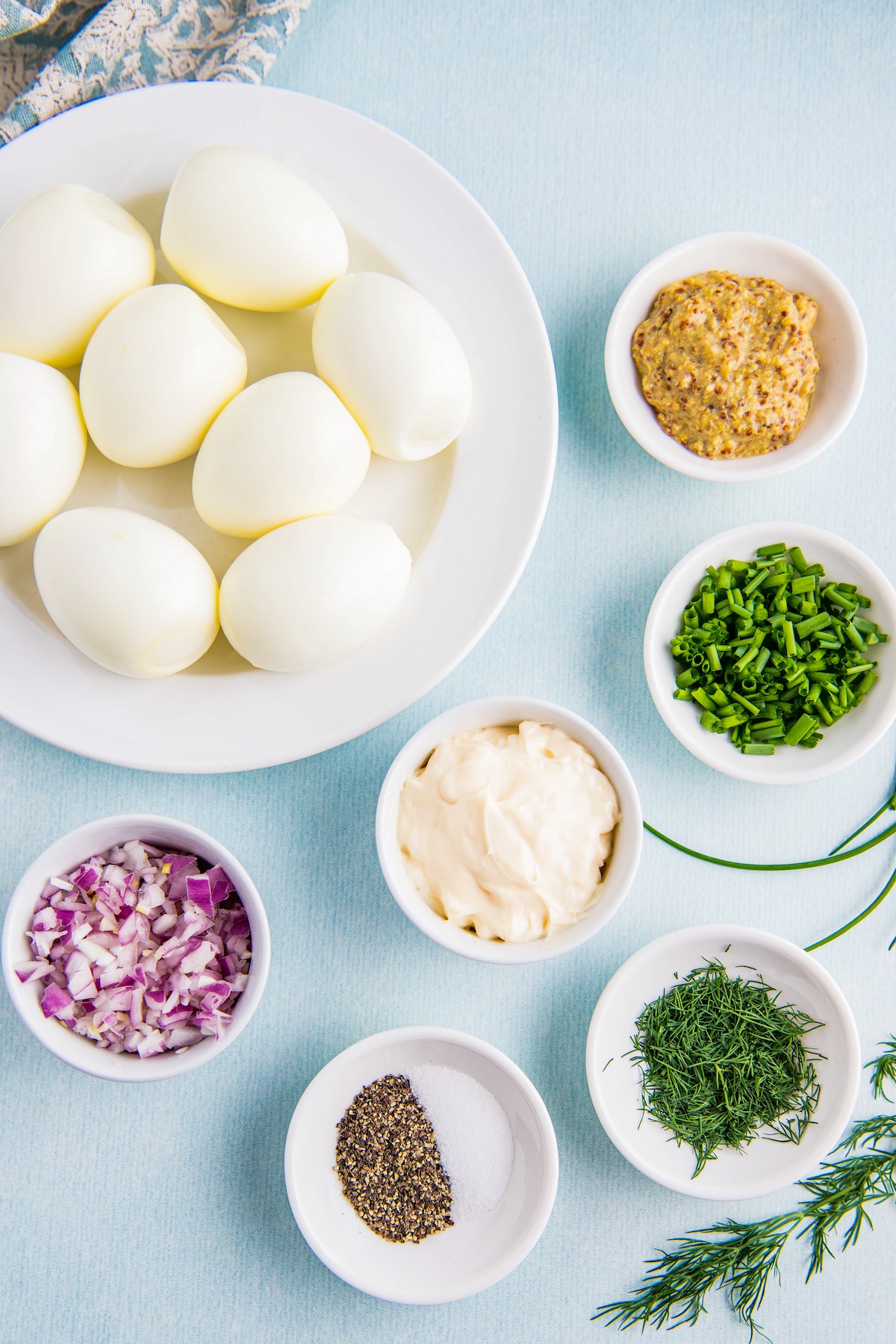 Ingredients for egg salad arranged in bowls.