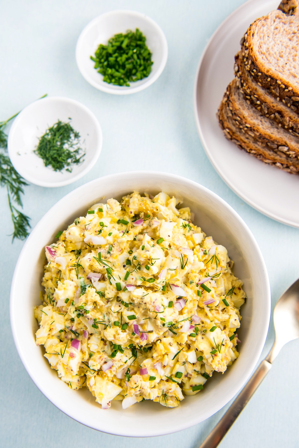 Egg salad in a bowl with a plate of bread.