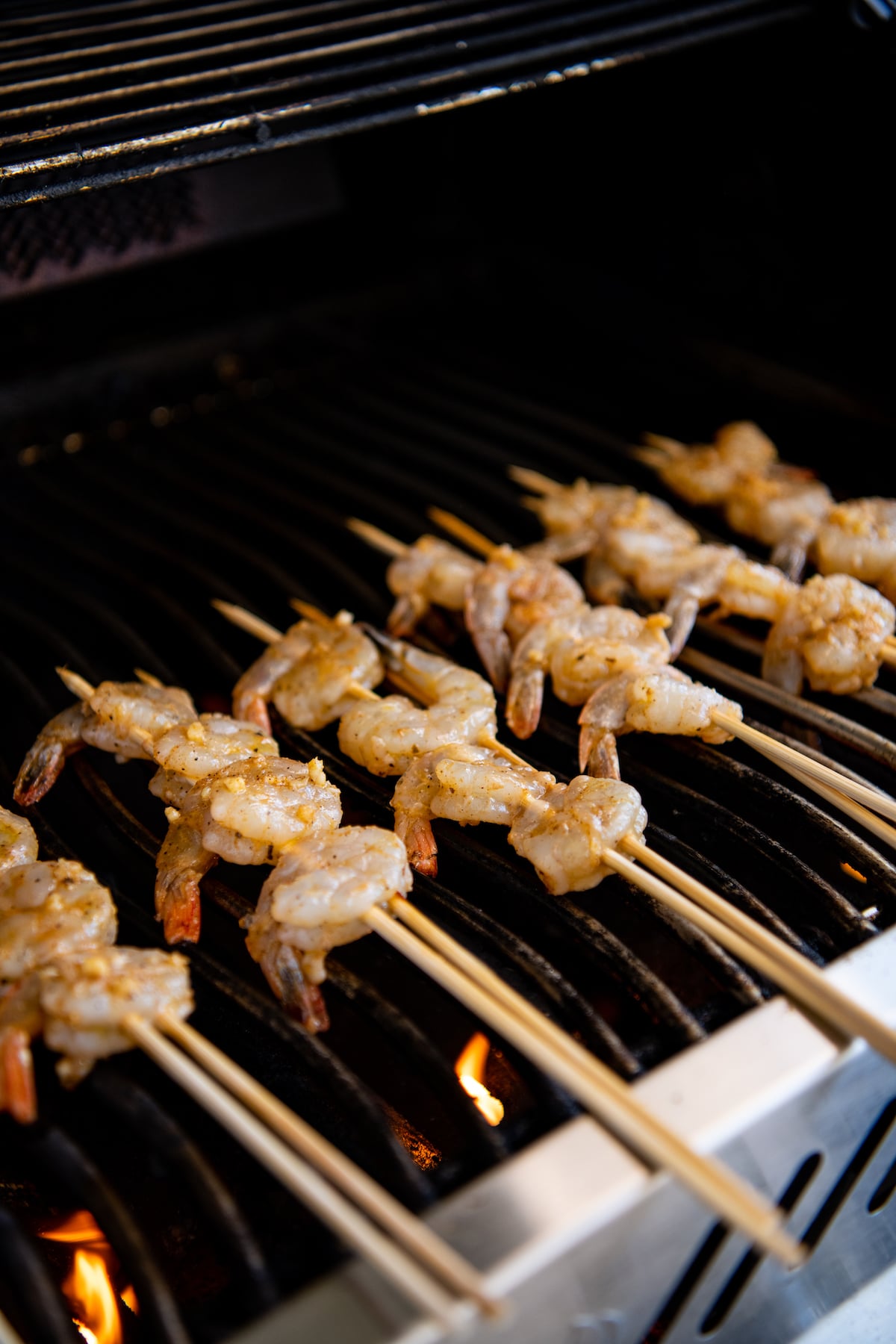 Raw shrimp on skewers on a grill.