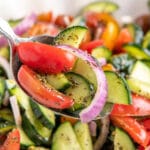 Up close image of tomato and cucumber salad being scooped up with a spoon.