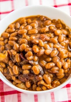 Baked beans in a white bowl on a picnic table.