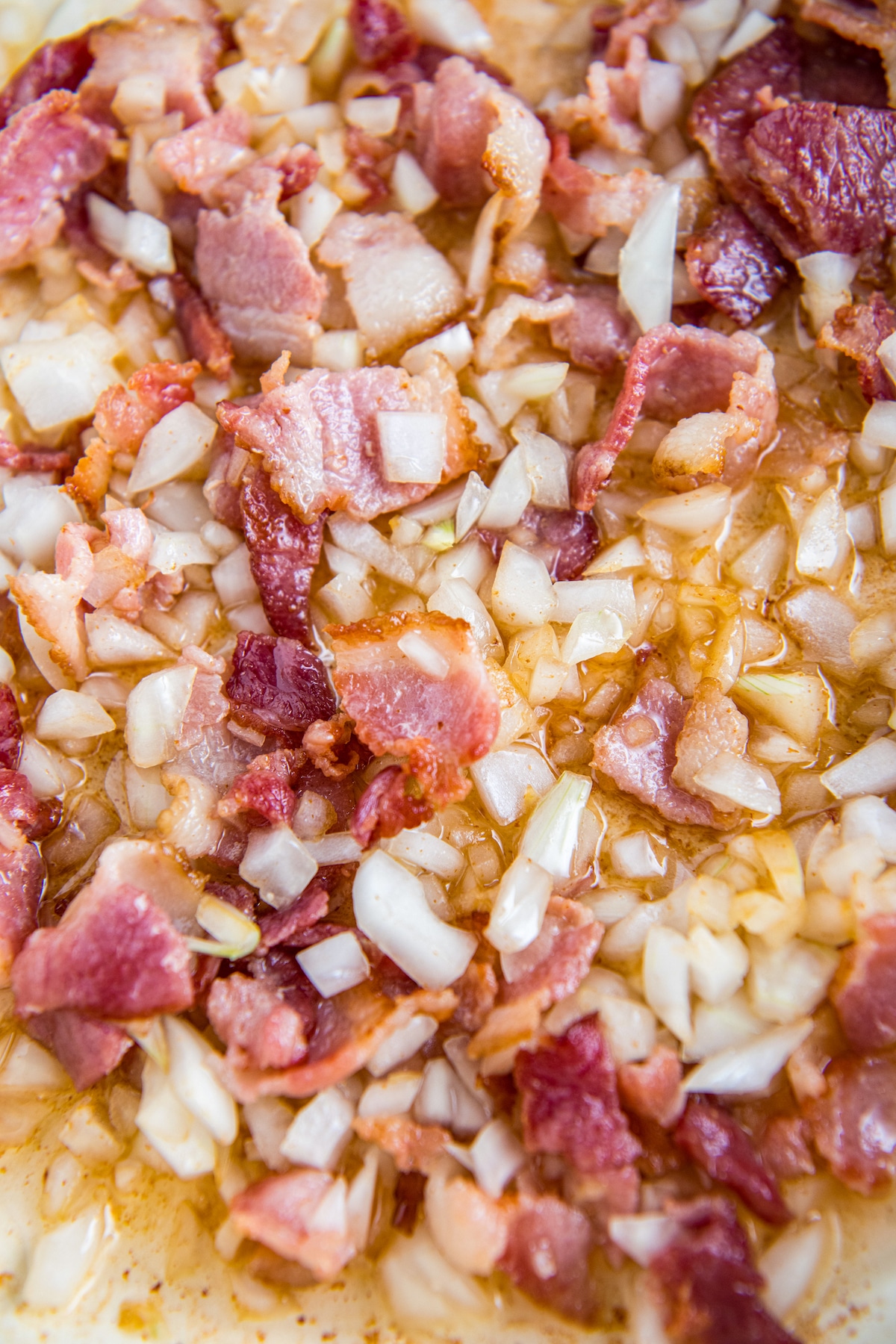 Onions and bacon sautéed together in a skillet.