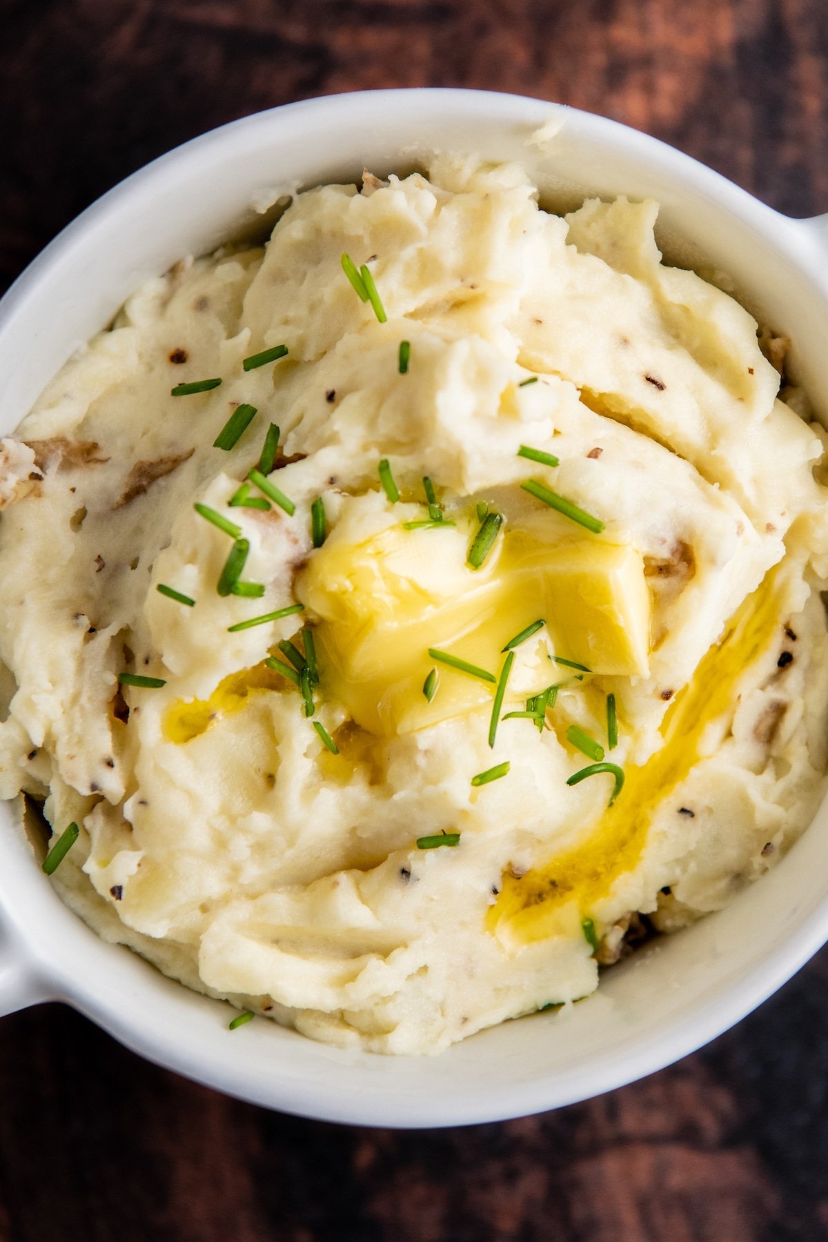Sour Cream mashed potatoes in a bowl with melted butter and chives on top.