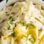 Best mashed potatoes in a crock with butter and chives on top.