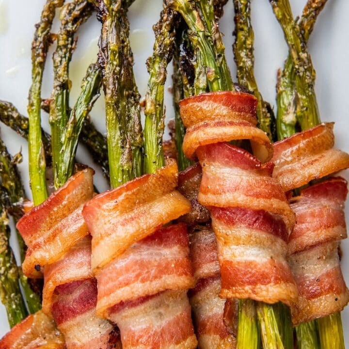 Bacon wrapped asparagus on a white plate.