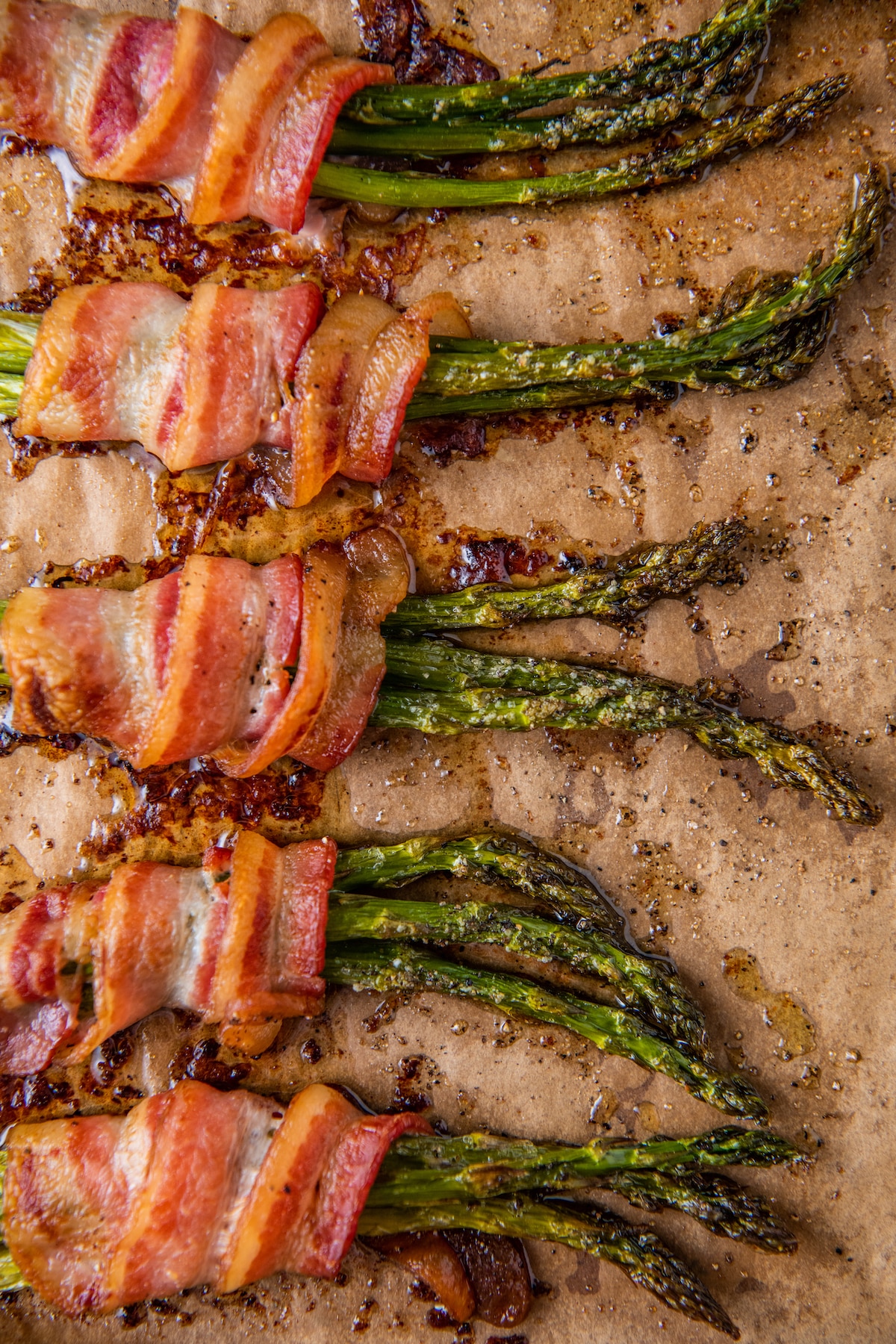 Cooked bacon wrapped asparagus on parchment paper.