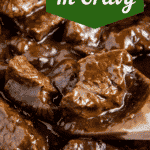 Beef tips in a skillet with a wooden spoon scooping them up.