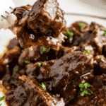 A bite of beef in brown gravy on a fork.