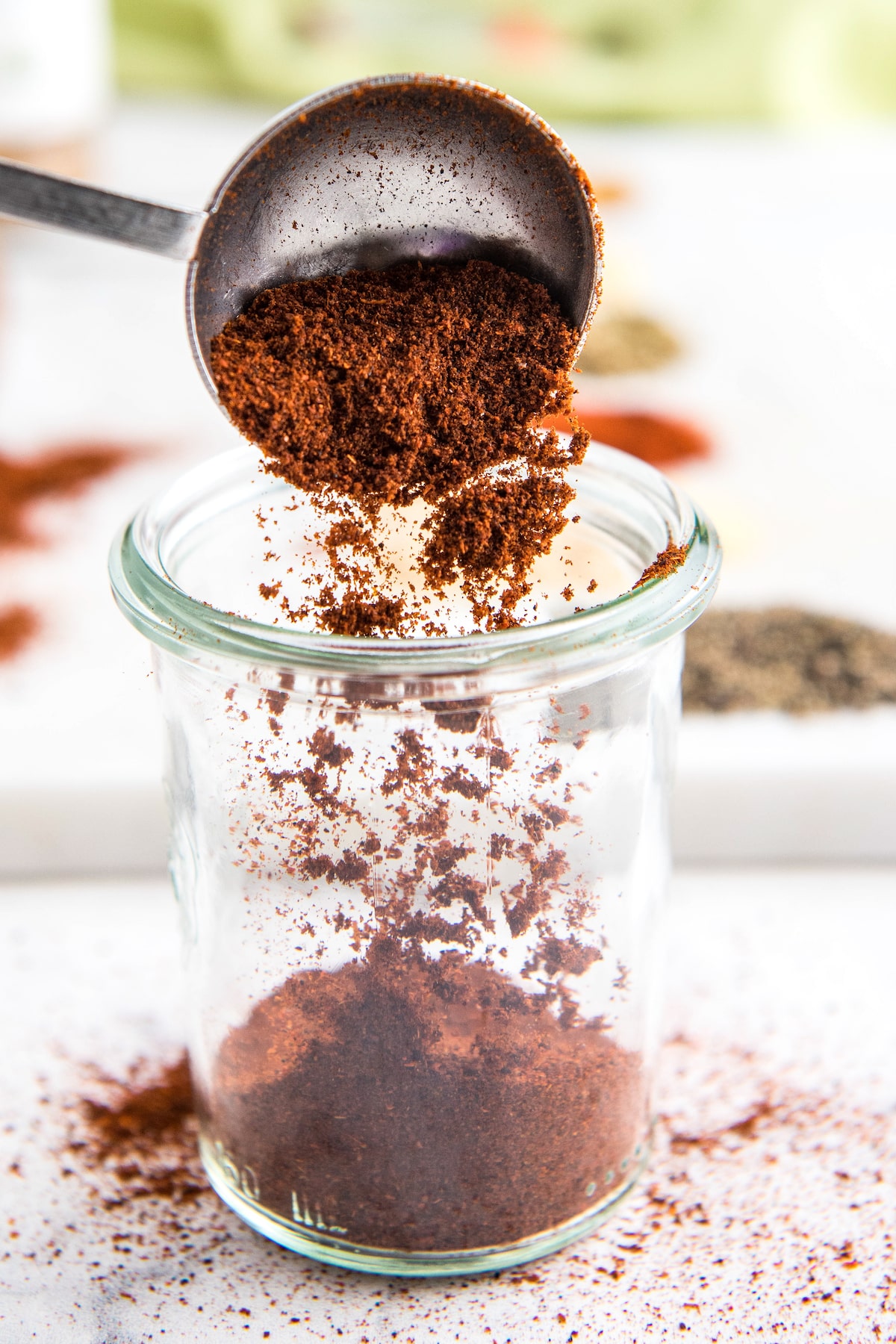 Chili powder being poured into a glass jar.