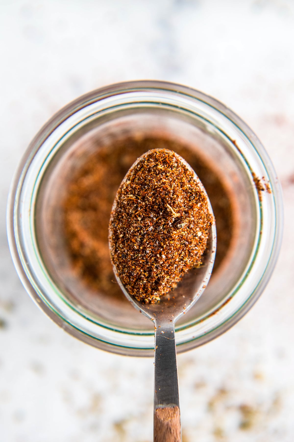 Homemade chili seasoning on a spoon in a jar.