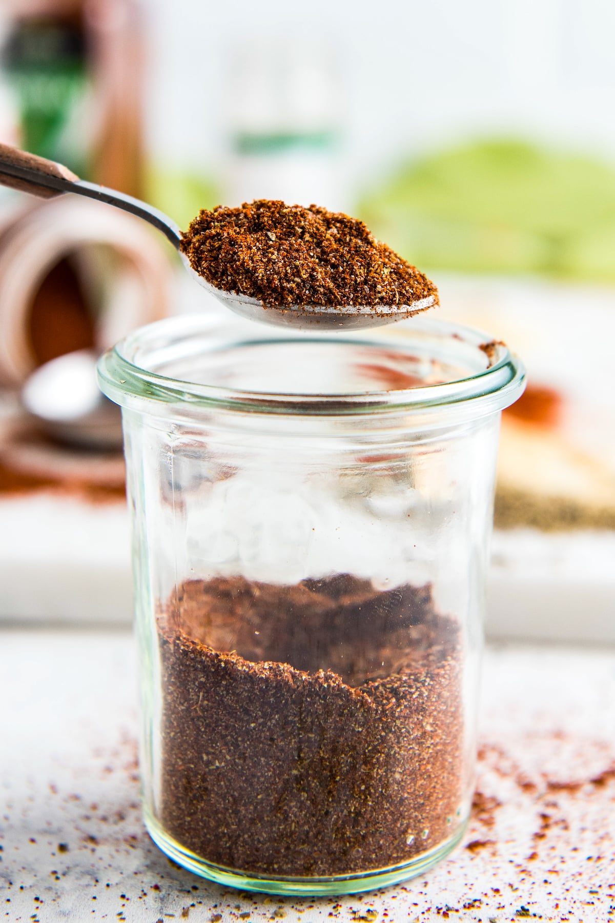 Chili seasoning on a spoon being scooped out of the glass jar.