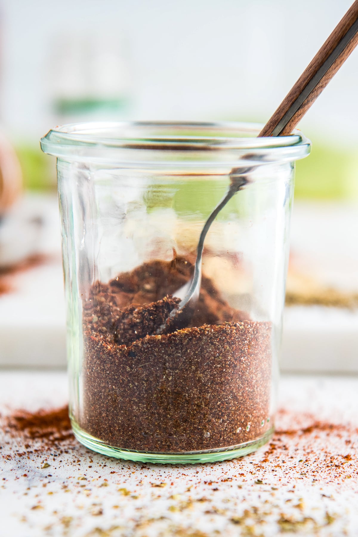 Herbs and spices mixed together in a glass jar for a homemade chili seasoning mix.