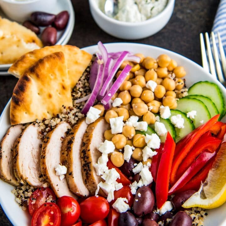 Greek salad in a white bowl with pita pieces.