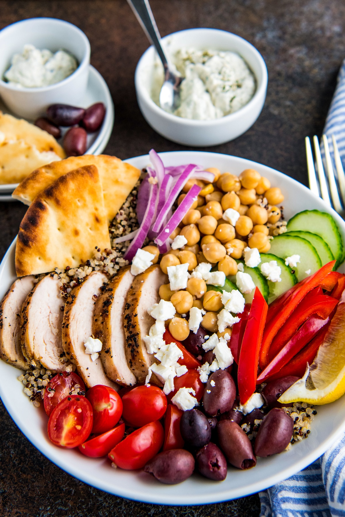 Greek salad in a white bowl with pita pieces.