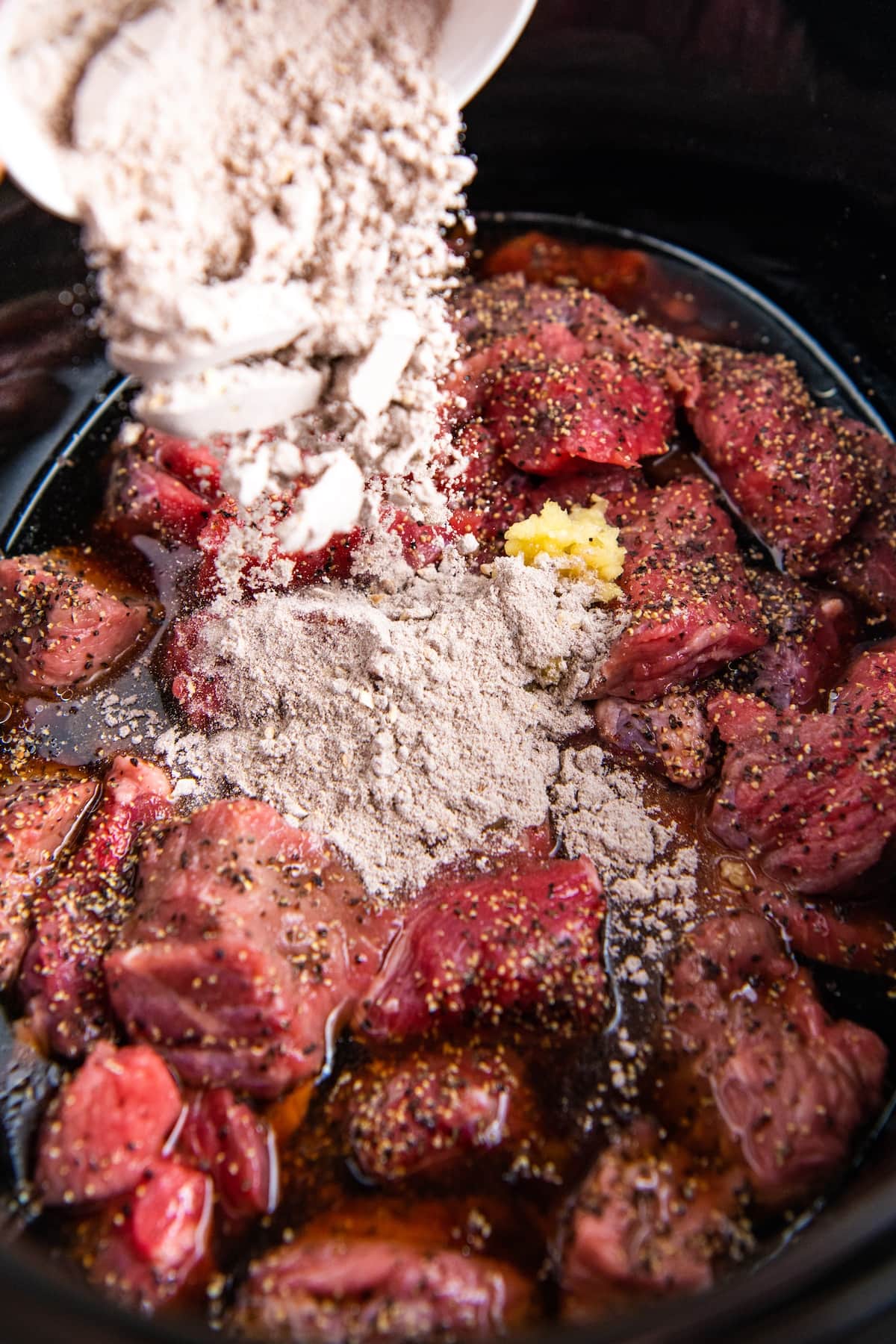 Gravy packets being poured into a crockpot with beef.