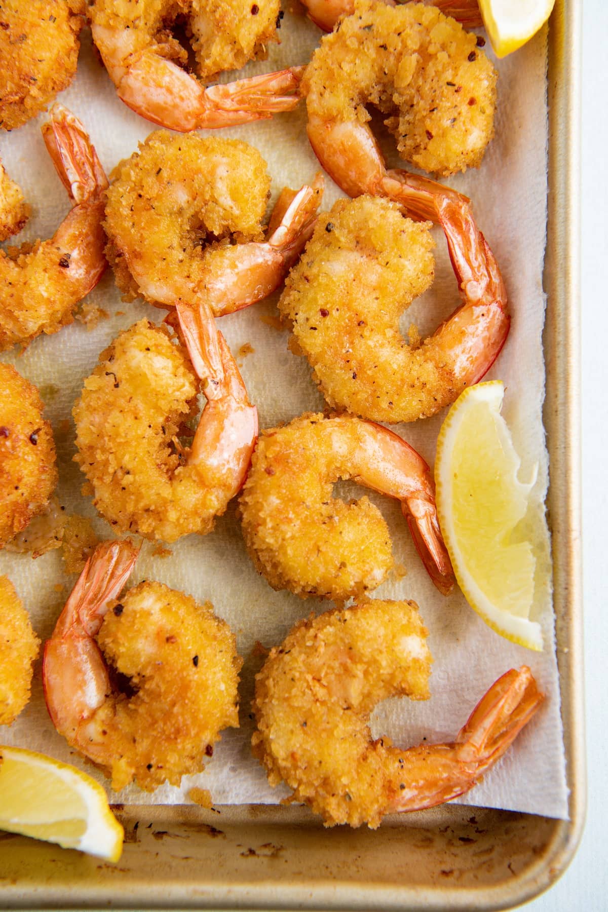 Shrimp draining after frying on a cookie sheet lined with paper towels.