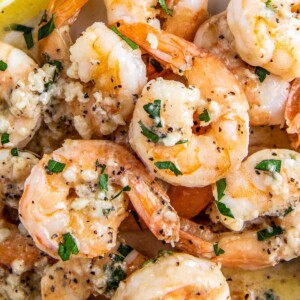 A plate with garlic shrimp in a lemon butter sauce with parsley on top.
