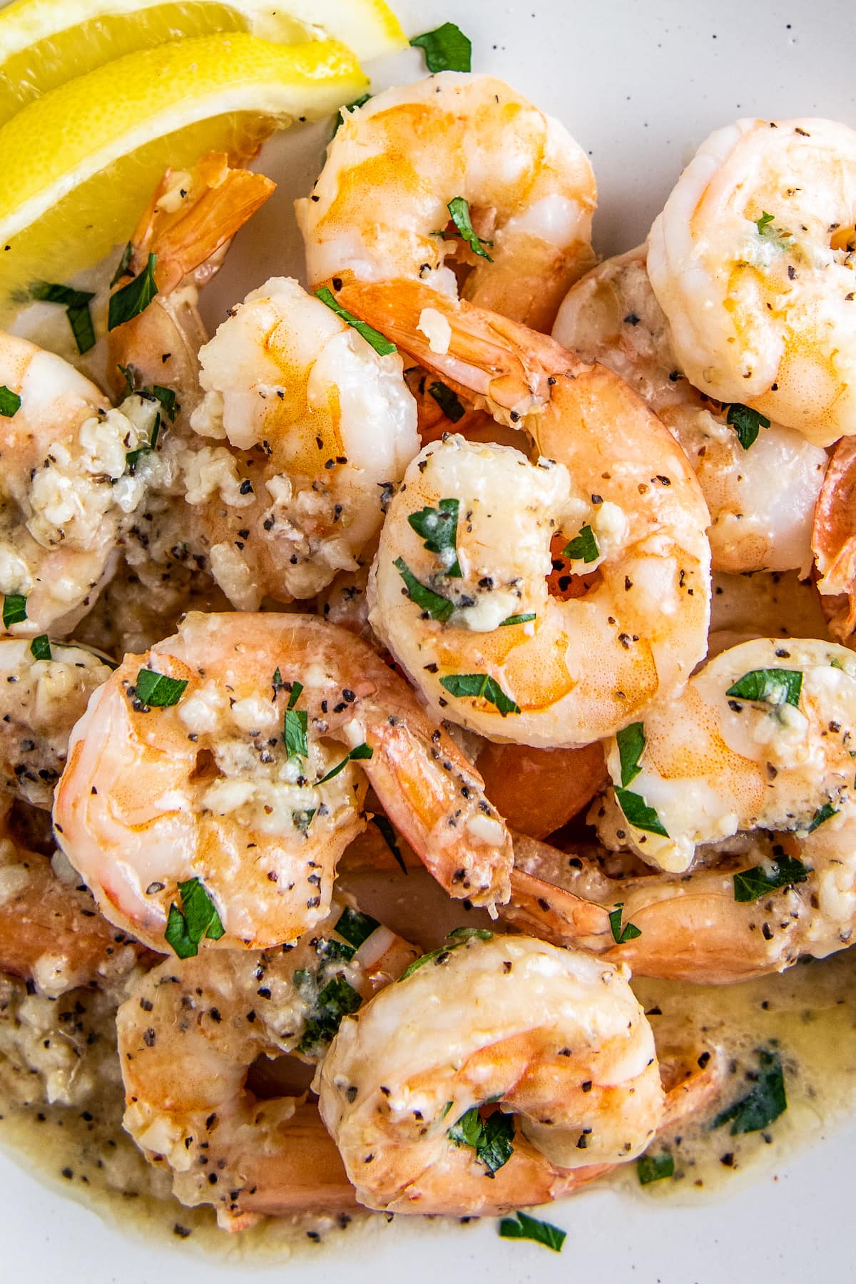 A plate with garlic shrimp in a lemon butter sauce with parsley on top.