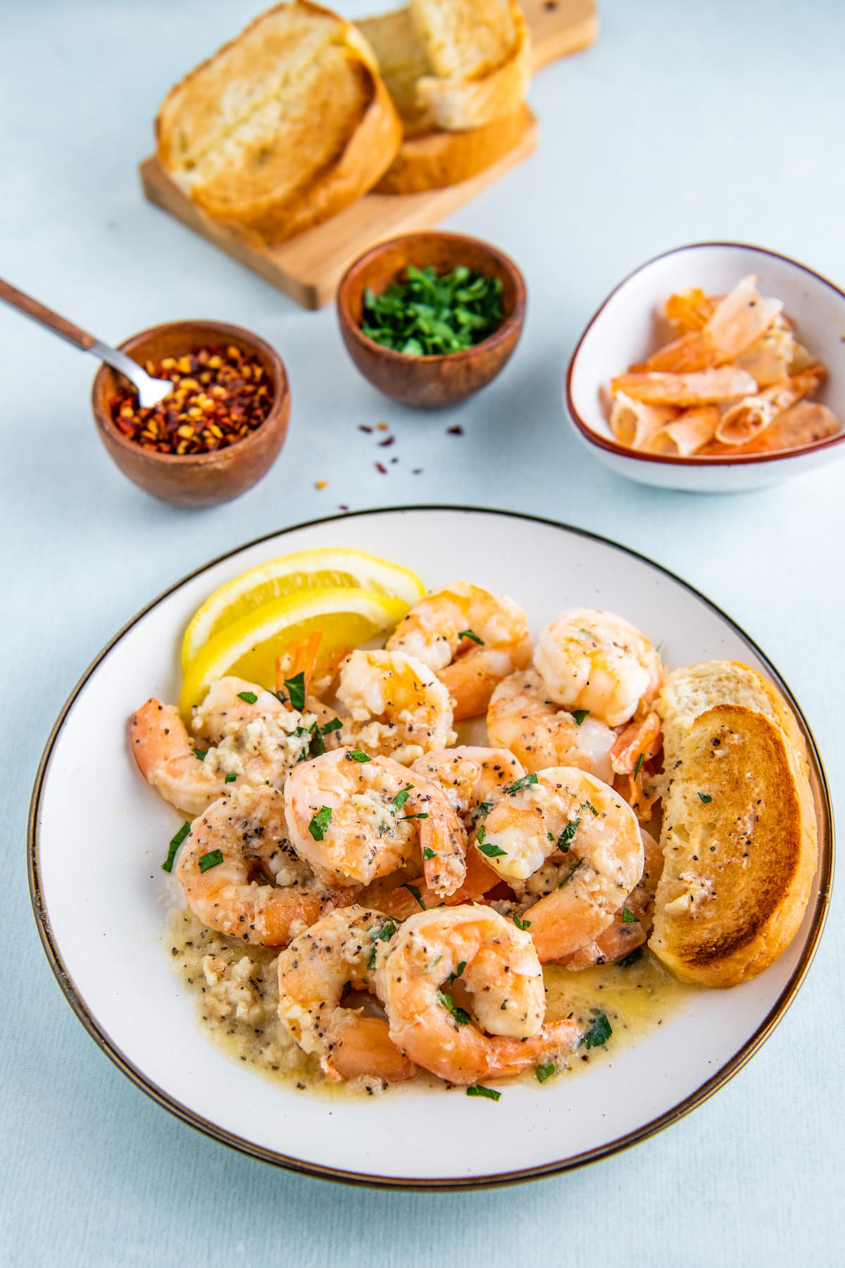 A plate of sautéed shrimp in a garlic butter sauce with garlic bread.