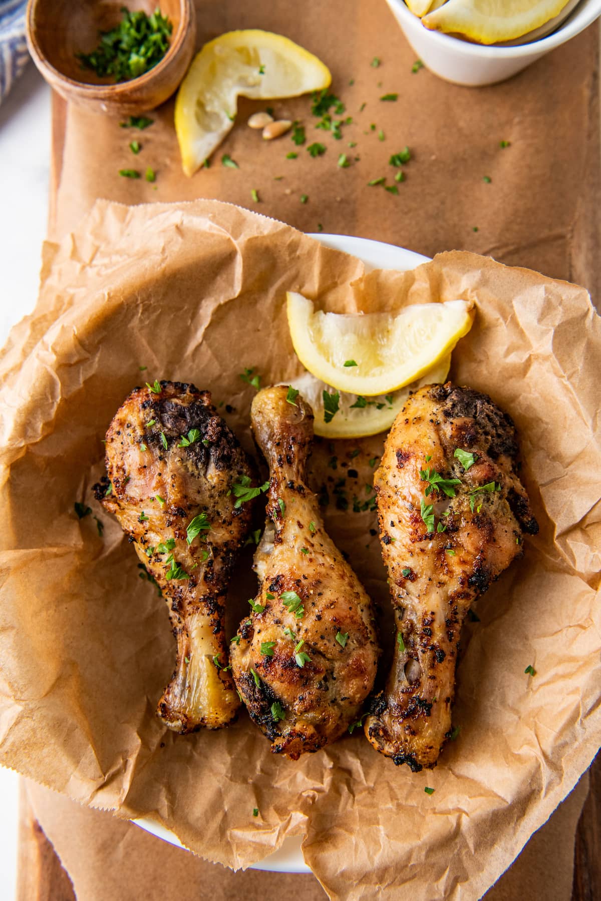 lemon pepper air fryer chicken drumsticks on a plate with a lemon wedge