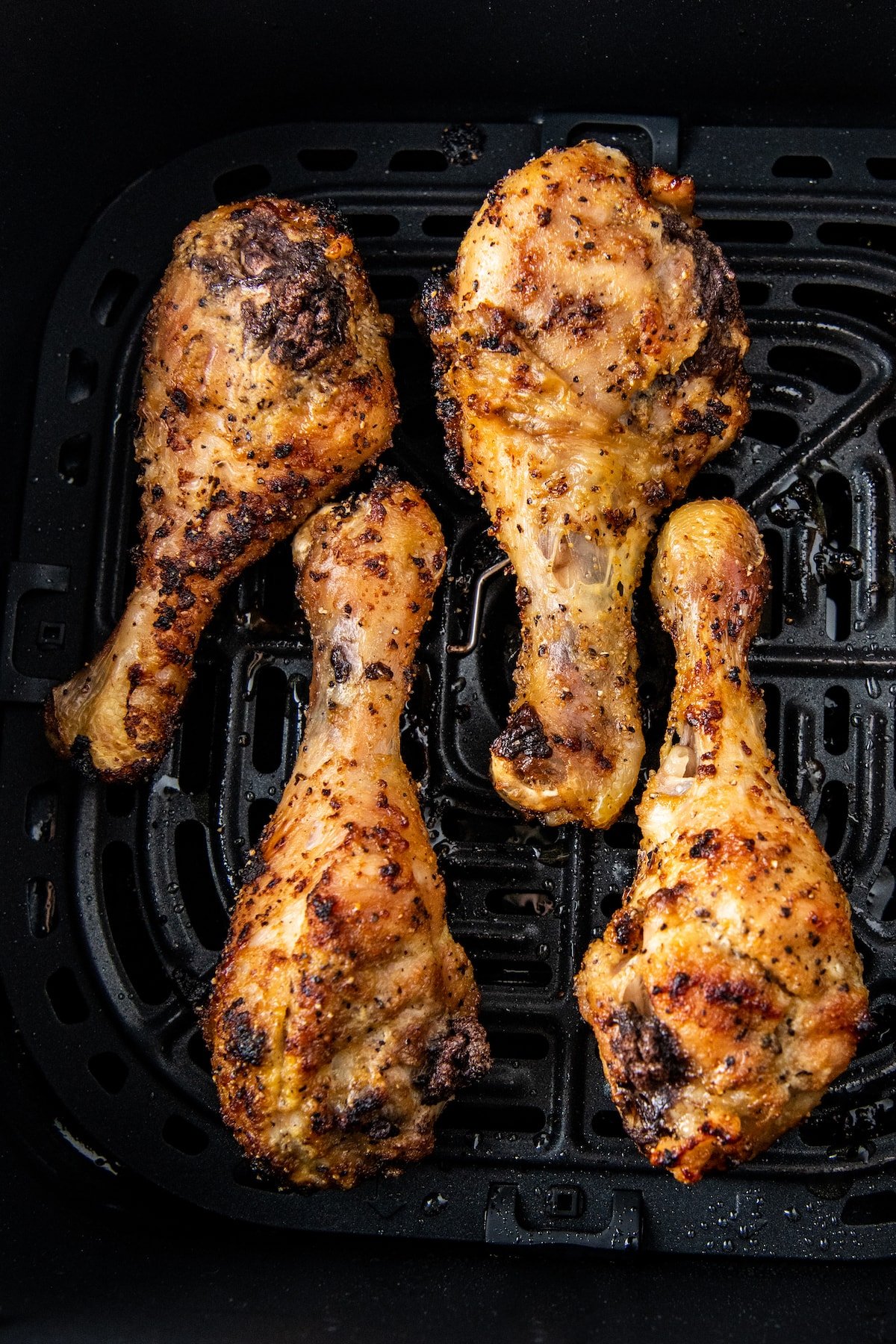 four cooked lemon pepper chicken drumsticks in an air fryer