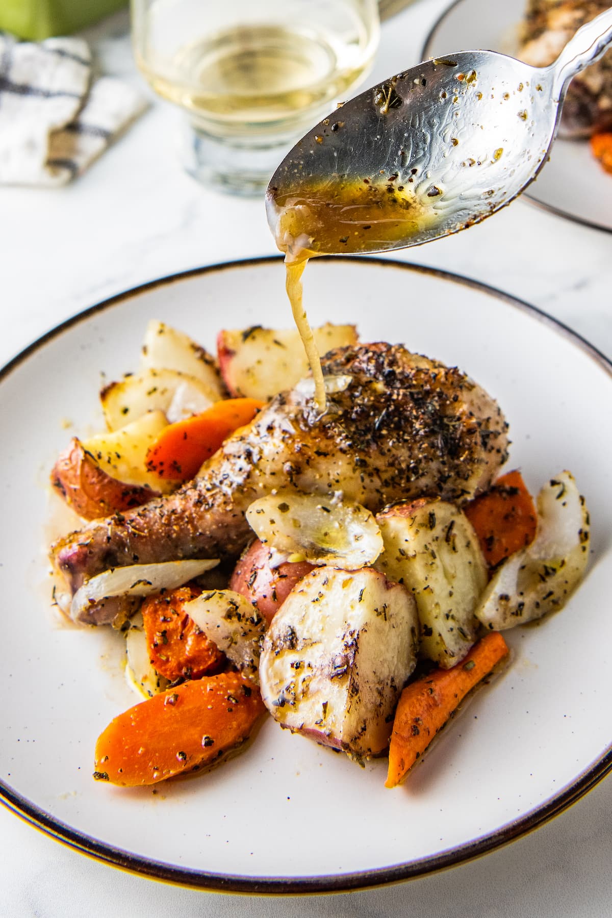 Plate with cooked chicken legs and vegetables and sauce being drizzled on top