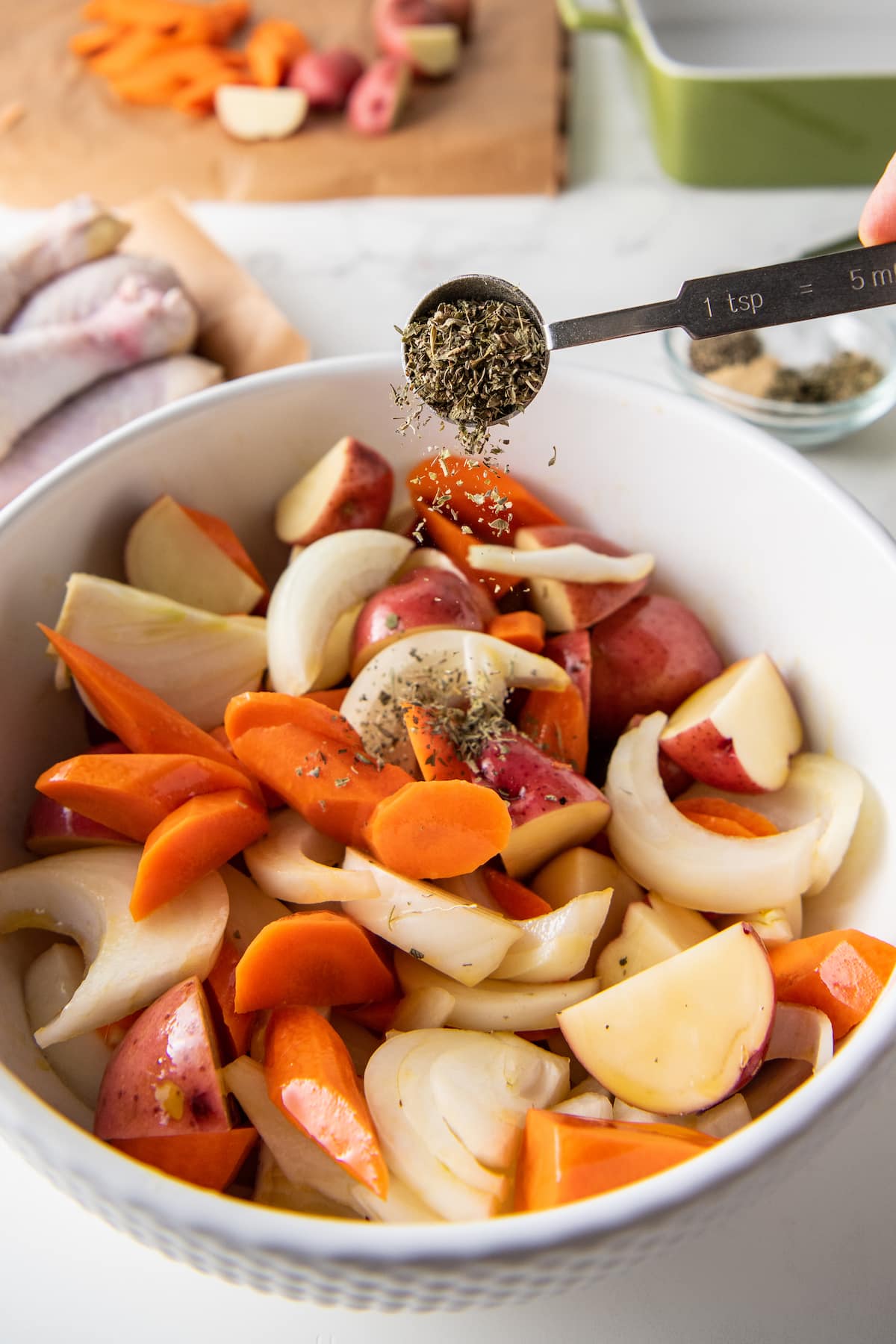 someone pouring a teaspoon of seasoning over an assortment of chopped vegetables