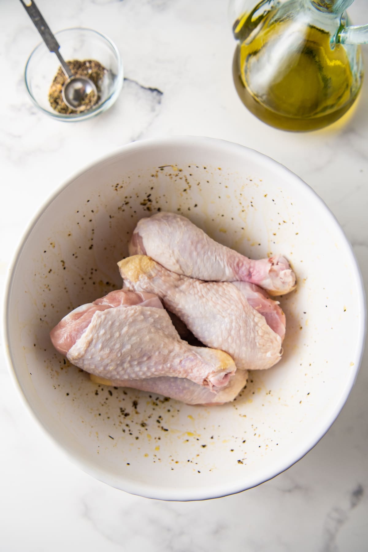 three uncooked chicken legs in a bowl