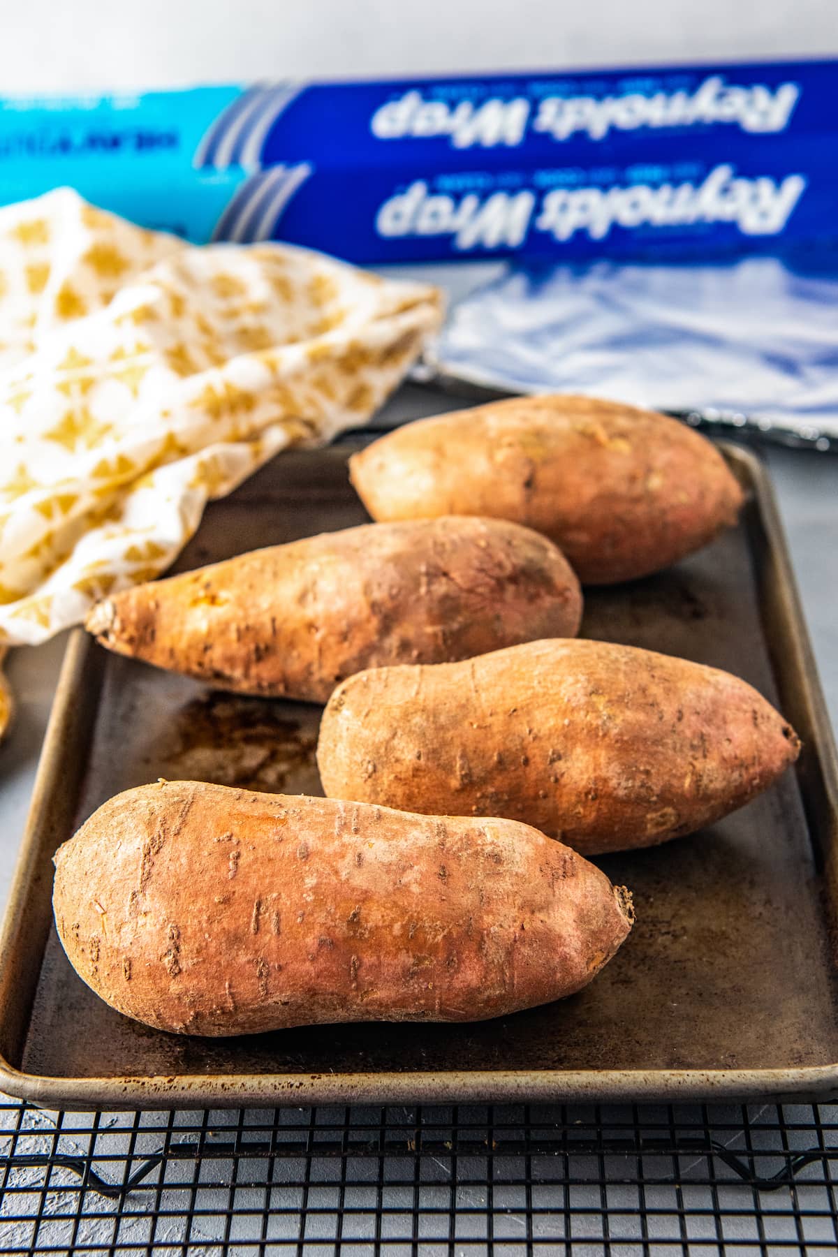 four sweet potatoes on a sheet tray