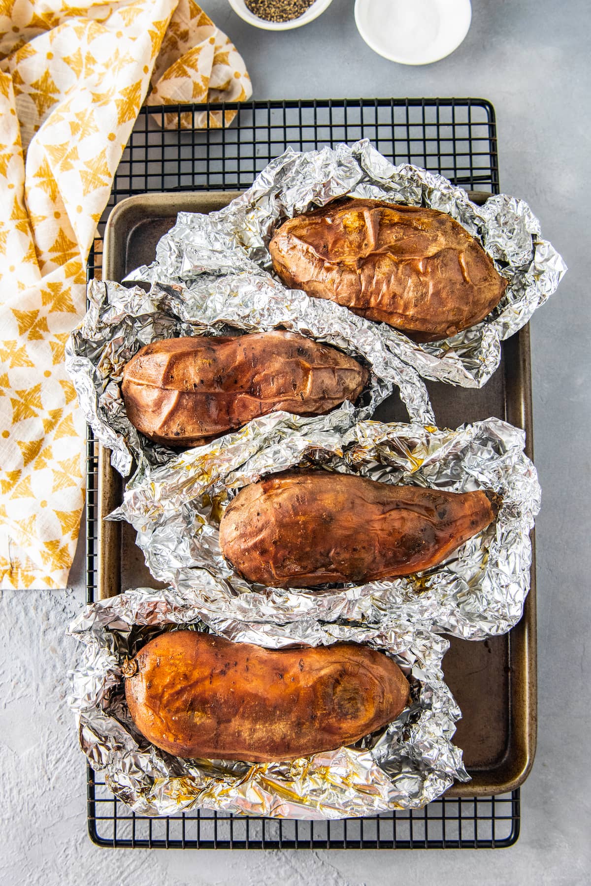 four cooked sweet potatoes semi-wrapped in foil