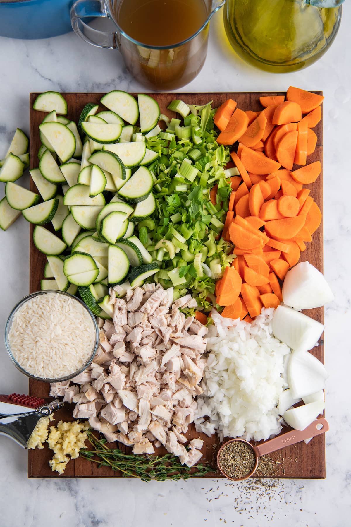 a cutting board with cut up vegetables, chicken, and other ingredients being put together to make soup