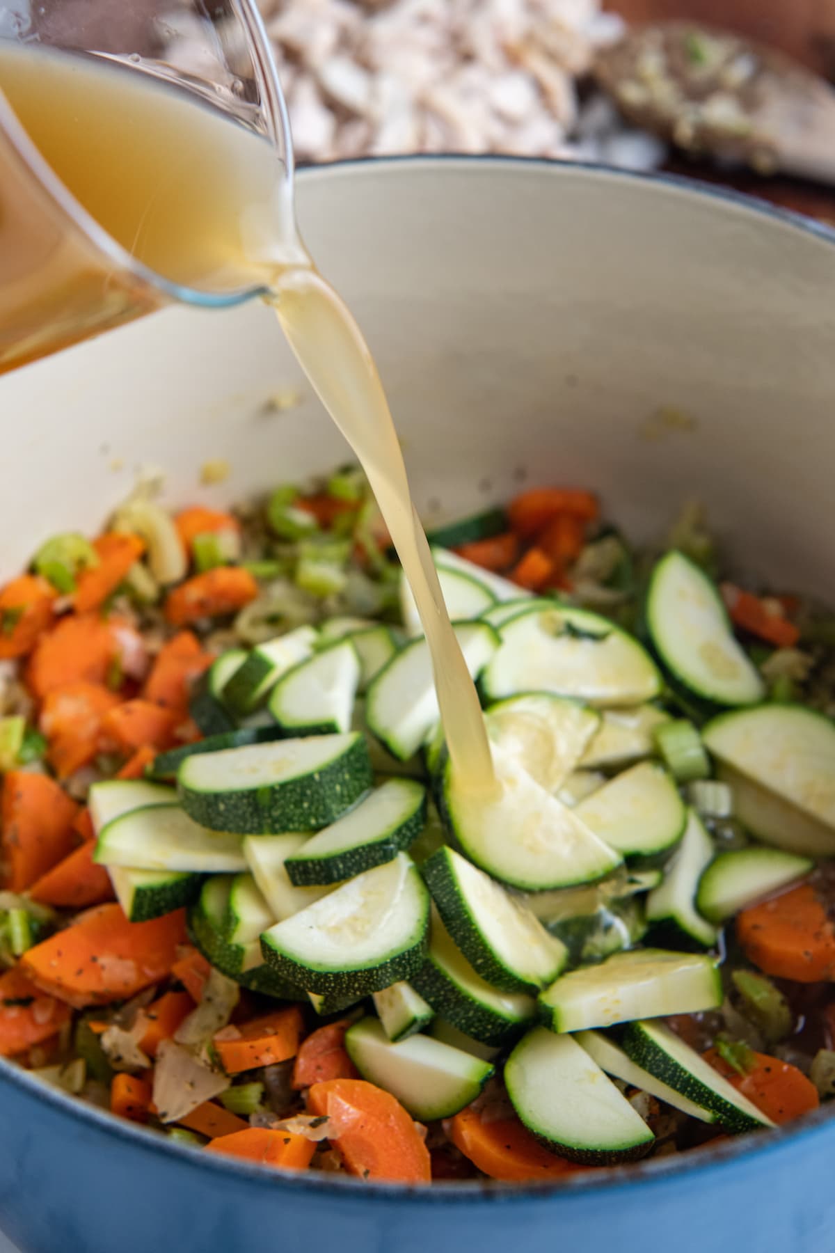 pouring stock into a pot with chopped vegetables