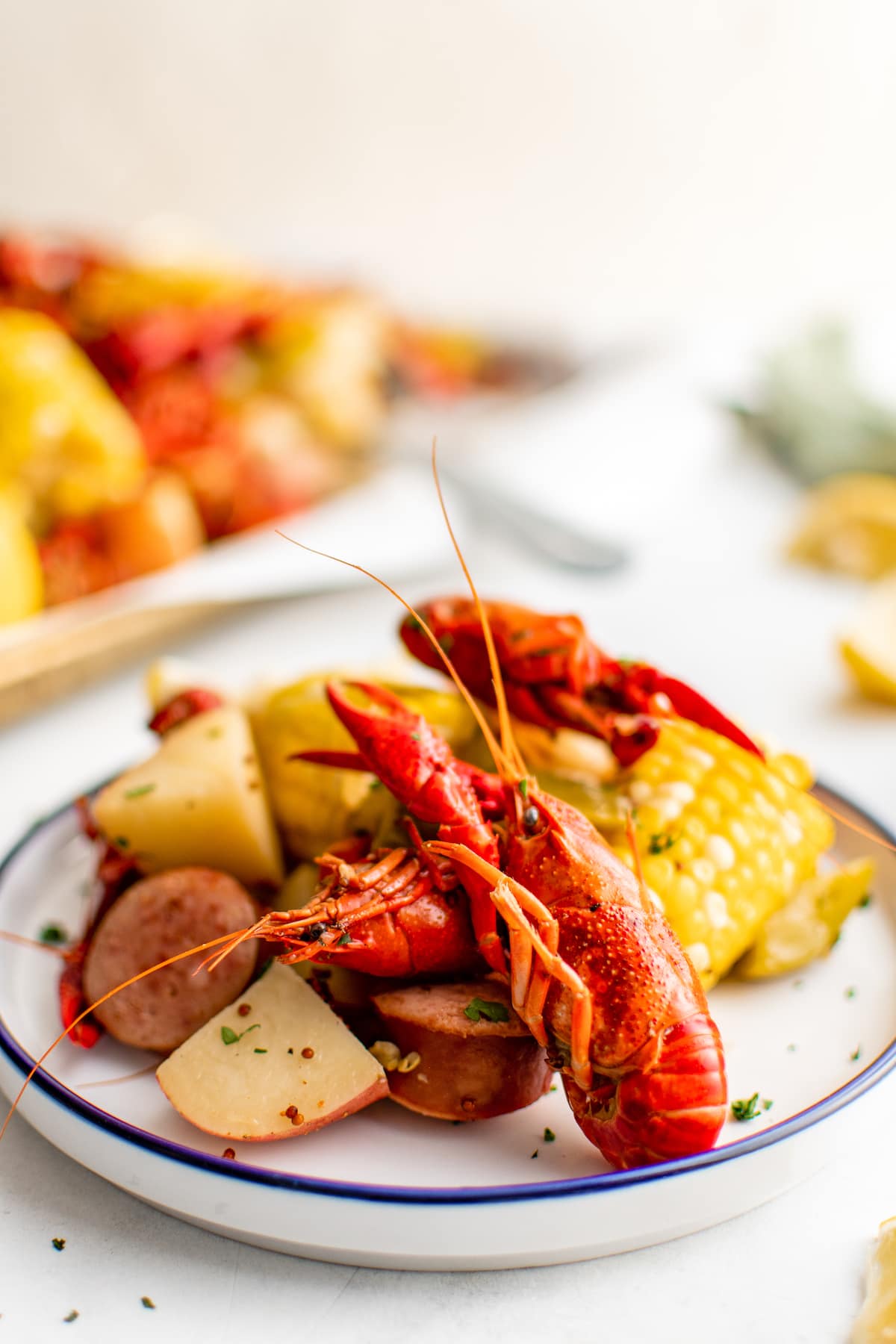 A white plate filled with crawfish, potatoes, corn and more.