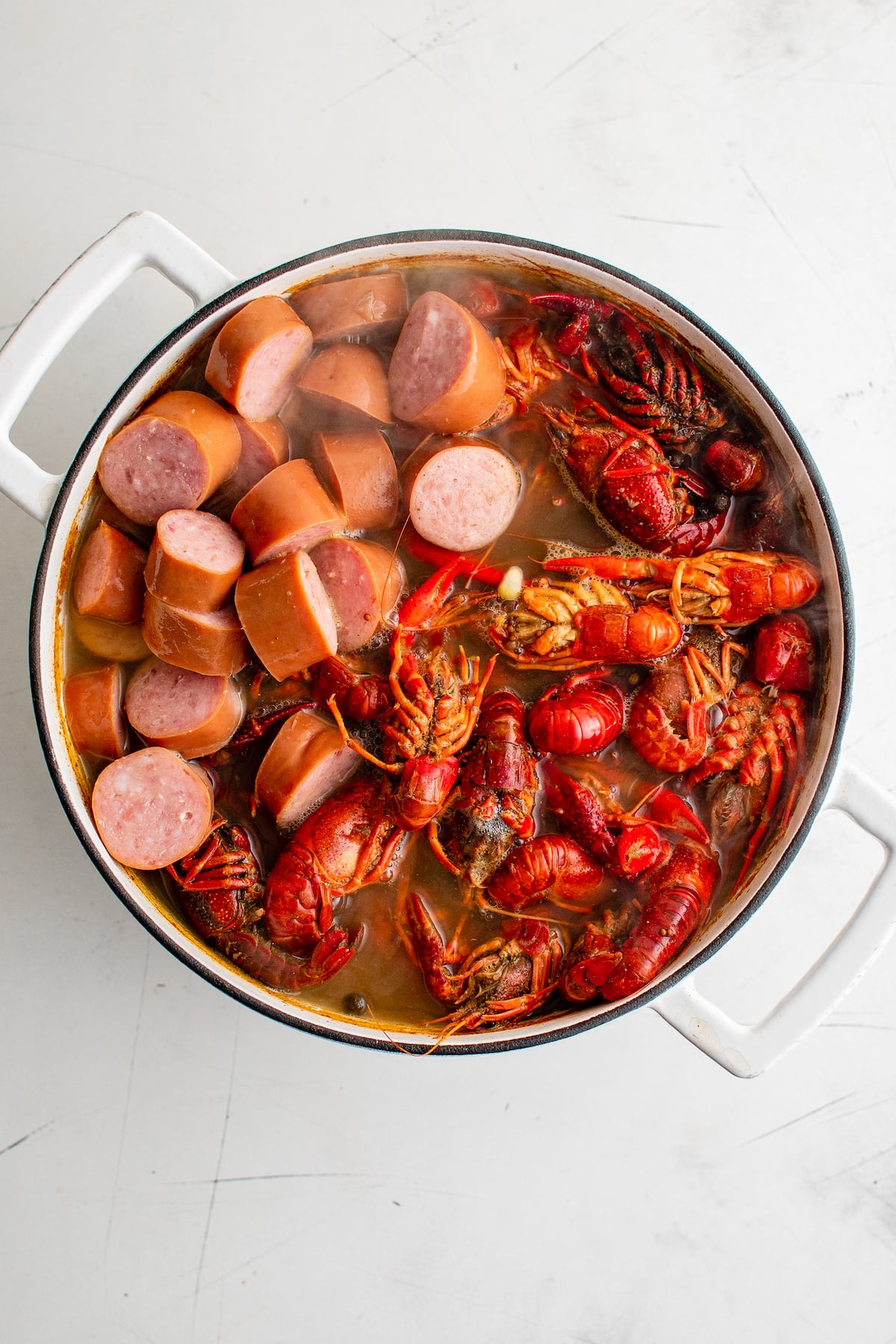 Crawfish and sausage in a pot with broth.